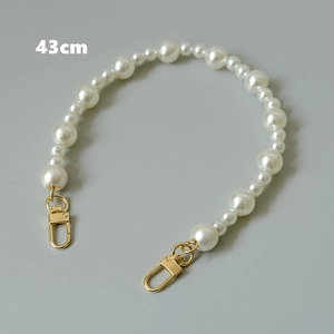 Détail d'une bandoulière en perles blanches de 43cm avec fermoirs dorés chic