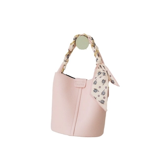 Light pink pebbled leather bucket bag featuring a gold chain handle wrapped in a silk scarf