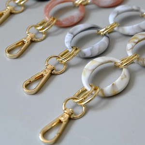 Macro detail of acrylic resin bag chain links with gold lobster clasps in multiple colors