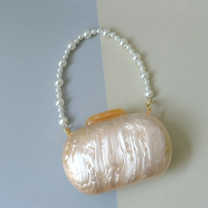 Détail du sac en résine à texture marbrée avec poignée en perles et fermoir en métal