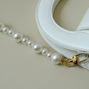 Détail d'un sac à main blanc avec perles dégradées et fermoirs métalliques dorés
