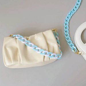 Detail of blue and white acrylic fishbone chain on a cream beige gathered pouch bag