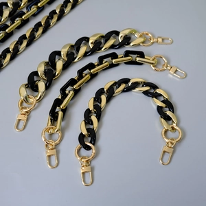 Makro-Detail der schwarz-goldenen Acrylharz-Gliederkette mit goldenen Karabinerverschlüssen