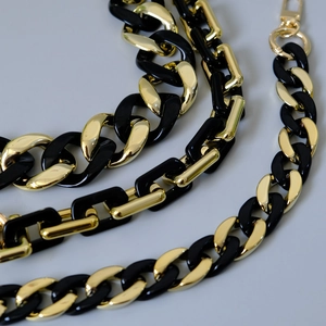 Detail der schwarzen Harz- und Goldmetallkette mit Karabinerverschluss