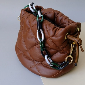 Detail view of brown quilted leather bucket bag with colorful resin acrylic handle chain