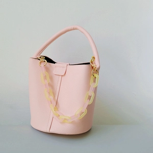 Dettaglio borsa a secchiello rosa con trama a grana litchi e catena in resina colorata
