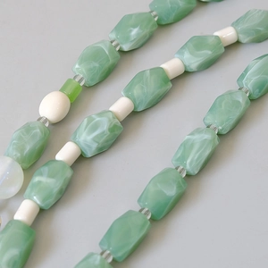 Detail of green marbled beads and white cylindrical spacers on a handmade strap