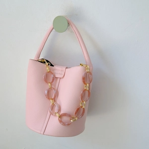 Pink litchi grain leather bucket bag with chunky amber acrylic chain and gold hardware