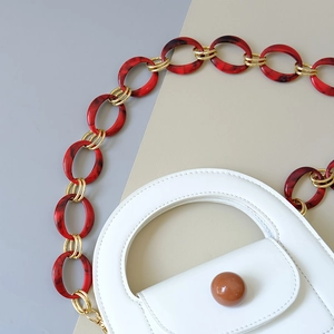 Detail of white leather handbag with amber resin chain and gold metal links