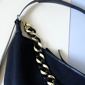 Detail der schwarzen Segeltuchtasche mit klobiger Harzkette und vergoldeten Gliederelementen