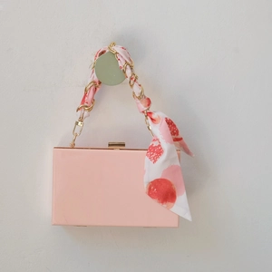 Détail de la pochette de soirée rose avec bandoulière en chaîne et foulard en soie