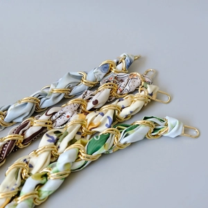 Detail view of woven silk scarf handbag straps with golden metal ring and lobster clasps