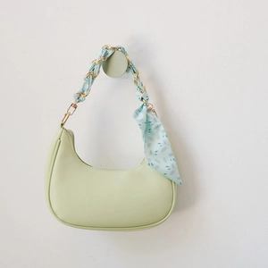 Détail du sac demi-lune vert clair avec foulard en soie sur la bandoulière chaîne dorée