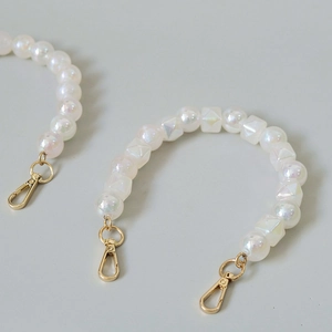 Macro shot of iridescent resin beads with golden lobster clasps for luxury handbags