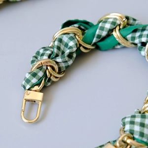 Detail of gold metal chain woven with green gingham silk ribbon for handbag handles