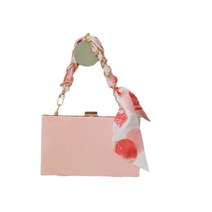 Sac à main rose rectangulaire avec chaîne en métal doré et accessoire foulard en soie décoratif