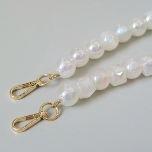 Detailed close-up of iridescent acrylic beads and gold lobster clasps for bag straps