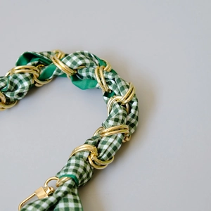 Detail of green and white checkered fabric woven with gold chain bag strap handle