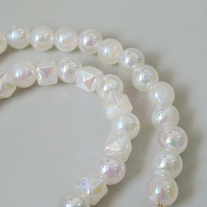 Macro detail of iridescent pearlescent beads and faceted cubes on a vintage handmade chain