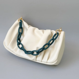 Detail of creamy white pleated cloud bag with chunky dark green resin chain strap