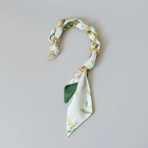 Close-up of golden metal chain handle wrapped in floral silk scarf with lemon print