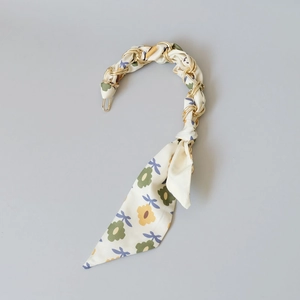 Detail of silk floral fabric wrapped on a gold chain bag strap handle with clasp