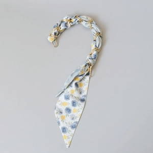 Detail of silk scarf handle strap with blue floral patterns and gold metal chain hardware