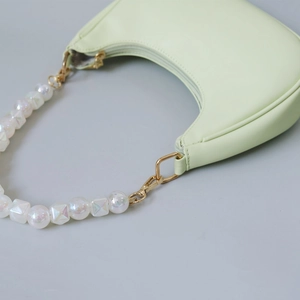 Detailed close-up of light green crescent bag with pearlescent beaded strap and gold hardware