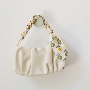 Detail of cream cloud bag featuring gold chain handle woven with floral silk scarf
