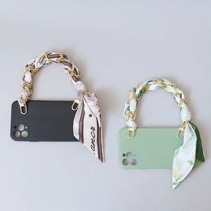 Detail of silk scarf chain handles on black and mint green phone cases with gold hooks