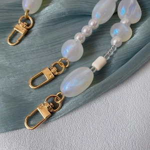 Close-up of iridescent acrylic beads and pearl chain with golden metal lobster clasp