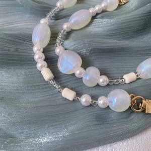 Close-up of handmade iridescent blue beads and white pearls with a gold metal clasp hook