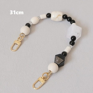Detalle de correa de bolso de perlas blancas y negras de 31cm con mosquetones dorados