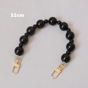 Detalle de correa de bolso de perlas negras de 32cm con cierres de mosquetón dorados y pulidos