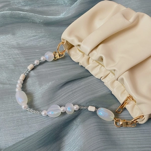 Detailed close-up of cream cloud bag with colorful iridescent beaded handle strap