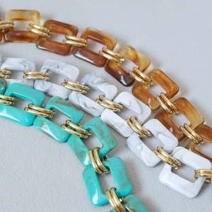 Detail showing amber, white, and green resin chain straps with golden metal link rings