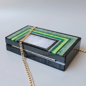 Detail of green striped acrylic evening clutch bag with marble texture and gold chain strap