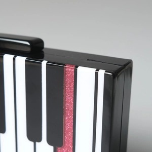 Détail d'une pochette en acrylique à touches de piano avec paillettes roses et fermoir noir