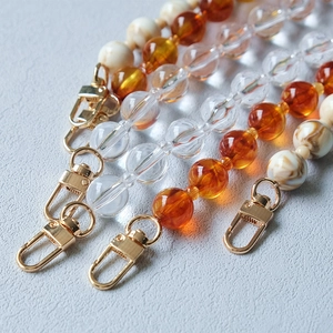 Detailed close-up of acrylic bead chains with golden swivel lobster clasps for bags