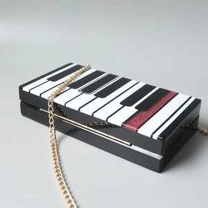 Détail de la pochette en acrylique clavier de piano avec paillettes rouges et chaîne
