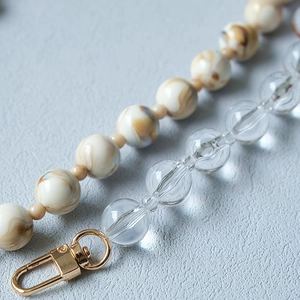 Macro detail of acrylic bead strap with cream marble beads and golden lobster clasp