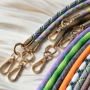 Detail of woven phone straps with premium gold metal clasps on silk background