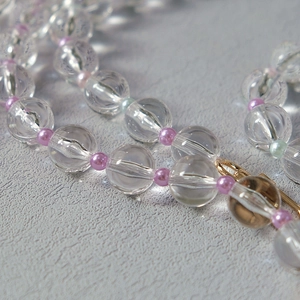 Detail of transparent acrylic bead strap with pink accents and golden lobster clasp