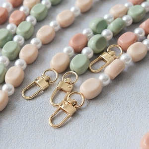 Close-up of Morandi colored acrylic beads and white pearls on strap with gold metal clasp