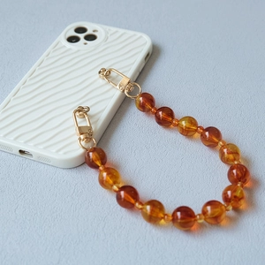 Detail view of amber resin bead strap with elegant gold metal lobster clasps for handbags