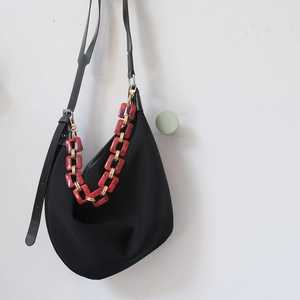 Detail of vintage acrylic chain with marble texture and gold metal links on black bag