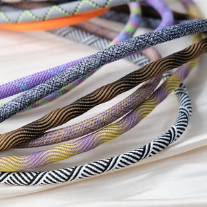 Close-up of woven crossbody phone straps in various colorful patterns on silk background