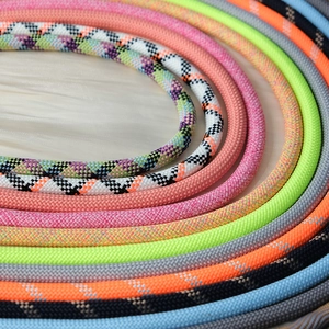 Macro detail of various colorful woven crossbody phone lanyards in a circular arrangement