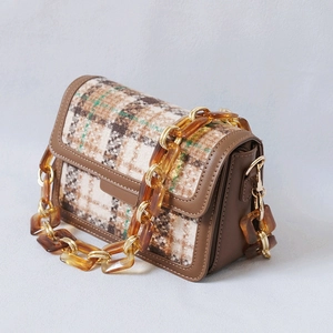 Detail of amber acrylic resin chunky chain on a vintage brown leather plaid bag
