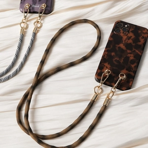 Detail of woven crossbody phone straps with gold metal hardware on silk background